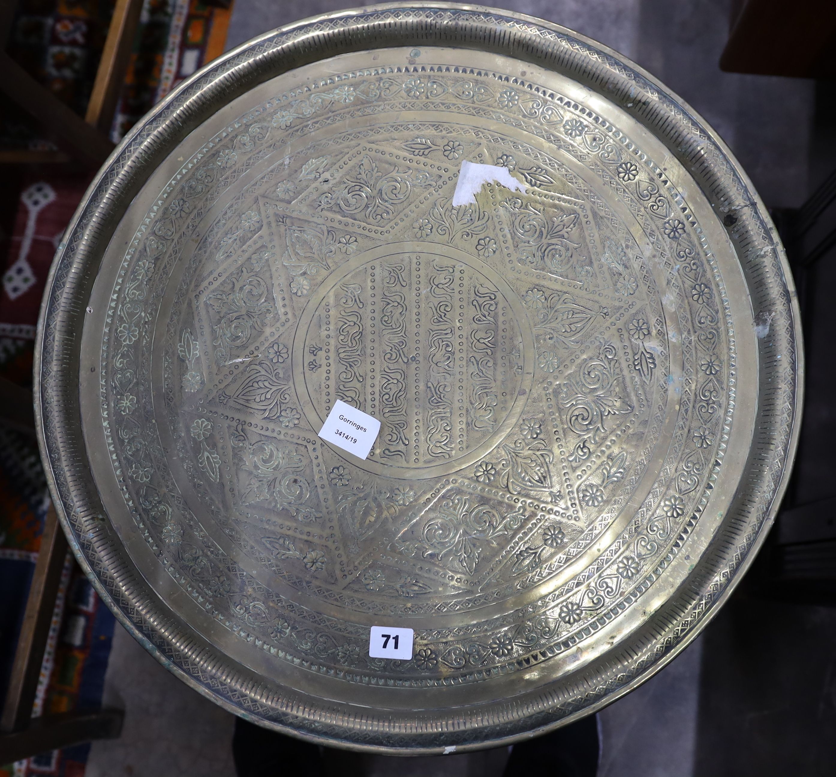 An Indian engraved brass circular tray top folding table, diameter 58cm, height 50cm